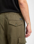 Person wearing olive green cargo shorts with a brand logo on a white background