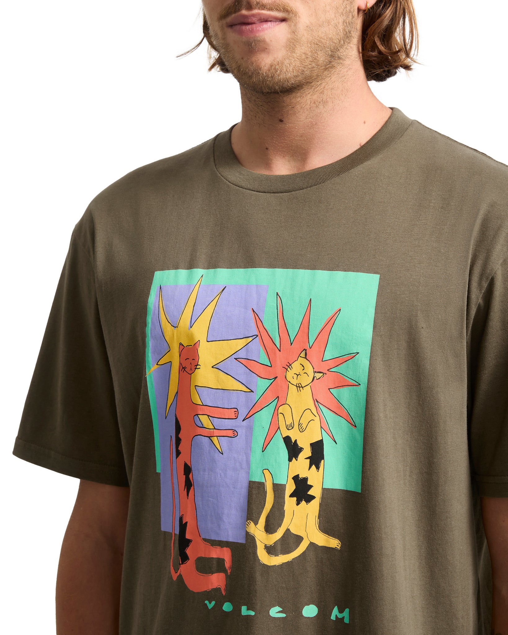 Person wearing a brown t-shirt with colorful graphic design and 'Volcom' branding.