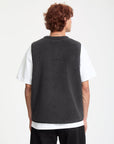 Person wearing a dark gray fleece vest over a white shirt on a white background