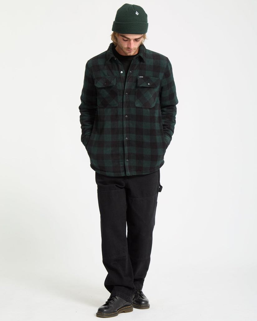 Person wearing a green plaid shirt, black pants, and a green beanie on a white background
