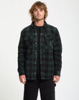 Man wearing a green and black plaid shirt on a white background