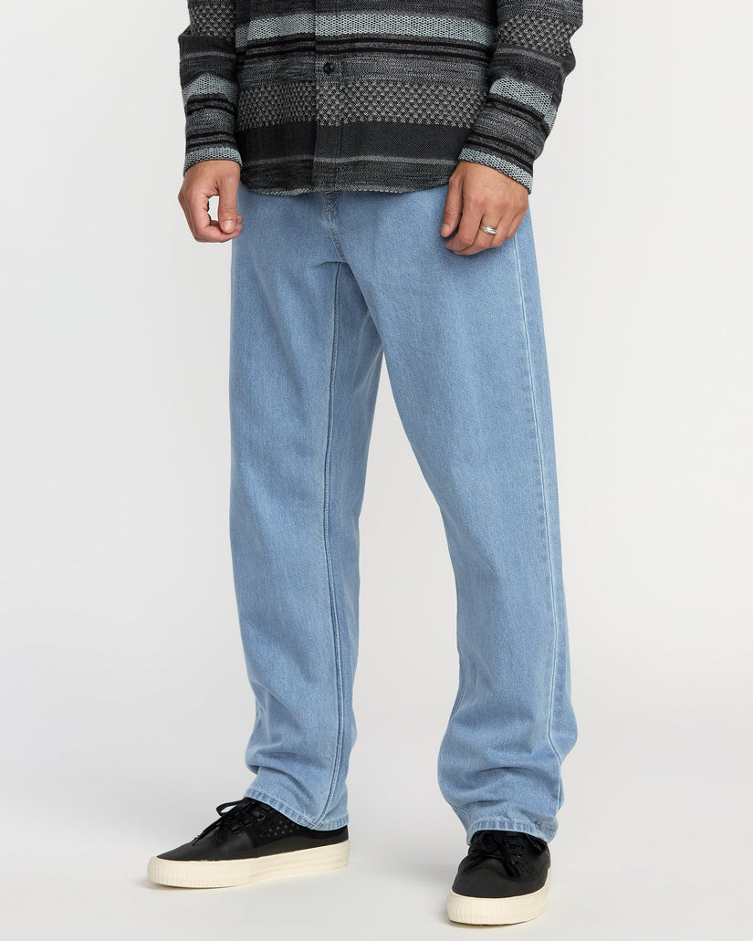 Person wearing light blue jeans and a patterned shirt on a white background
