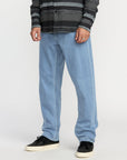 Person wearing light blue jeans and a patterned shirt on a white background