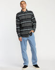 Man wearing a patterned shirt and jeans on a white background