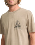 Man wearing a beige Volcom t-shirt with a logo on a white background