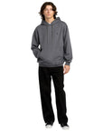 Person wearing a gray hoodie and black pants on a white background
