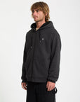 Man wearing a black hoodie with a small logo on a white background