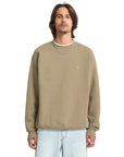 Man wearing a beige sweatshirt with a small logo on a white background