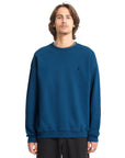 Person wearing a blue sweatshirt with a small logo on a white background