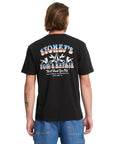 Person wearing a black t-shirt with colorful graphics and text on the back, standing against a white background.