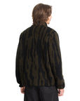 Person wearing a dark camouflage jacket on a white background