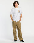 Man wearing a white t-shirt with a Voclom graphic design and brown pants on a white background
