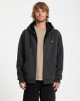 Man wearing a black hoodie with a small logo on a white background