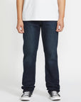 Person wearing dark blue jeans and a white shirt on a plain background
