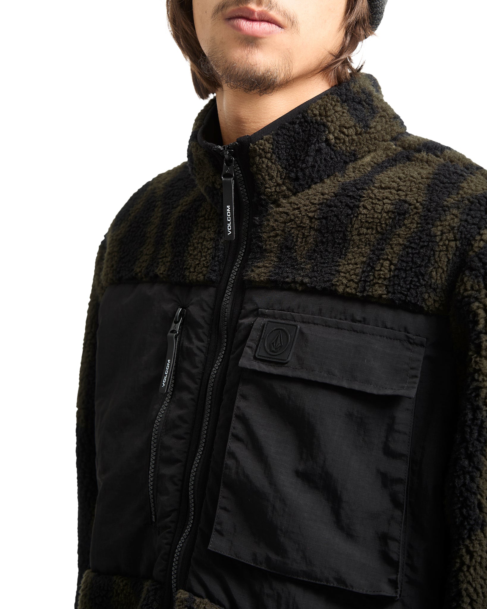 Close-up of a person wearing a black and green jacket with a white background