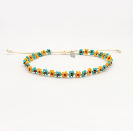 A beaded stretch bracelet featuring small daisy-like flowers in turquoise, yellow, and orange with a tiny silver heart charm, displayed on a clean white background.